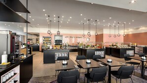 Un restaurante moderno con varias mesas y sillas, una zona de cocina y una isla central con exhibiciones de comida.