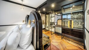 Una habitación de hotel moderna con cama, una división de vidrio y una zona de tocador.