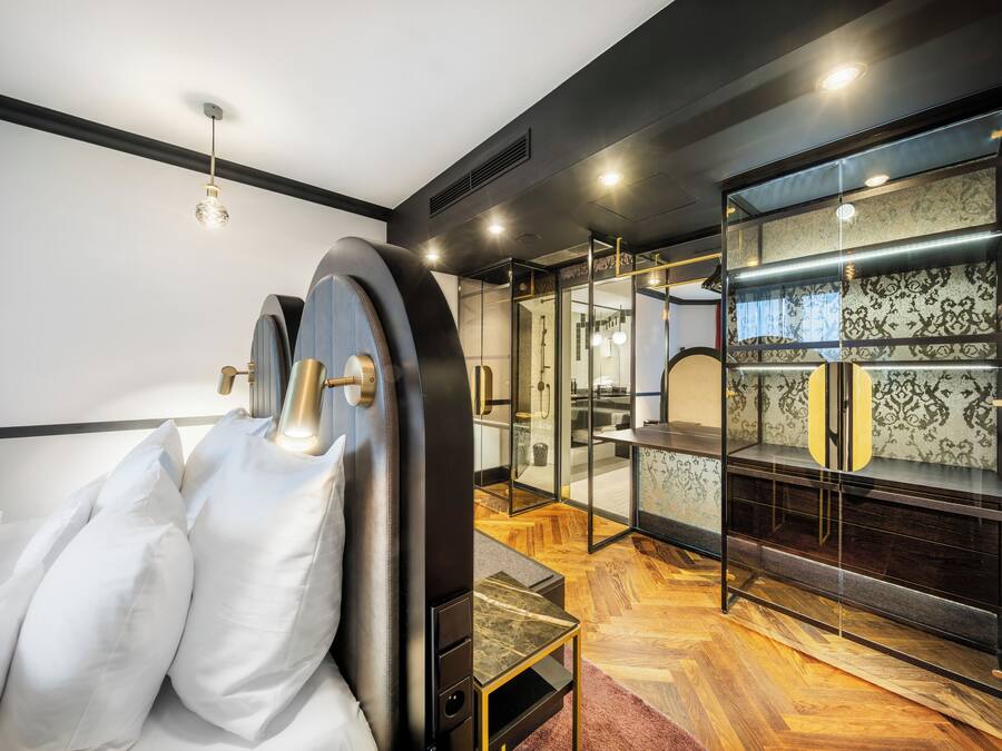 Una habitación de hotel moderna con cama, una división de vidrio y una zona de tocador.