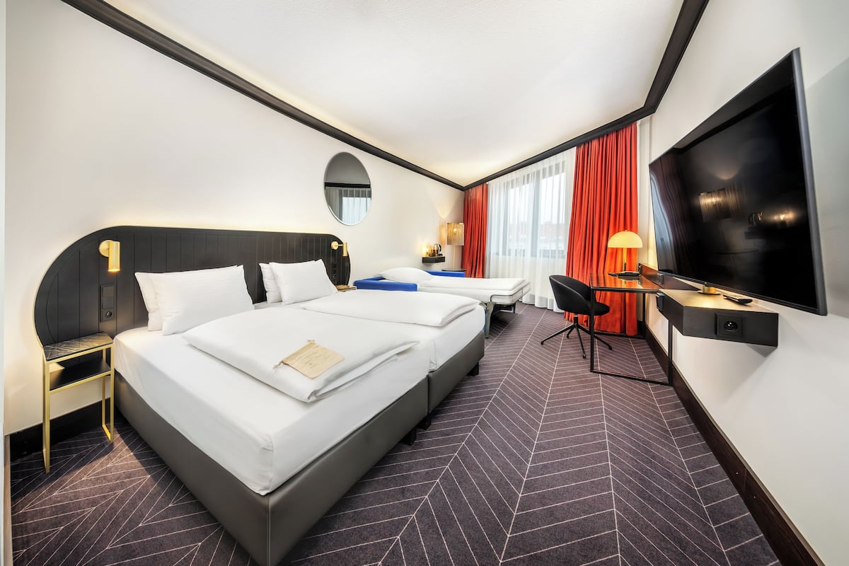 A hotel room with a large bed, a desk, a TV, and a bathroom.