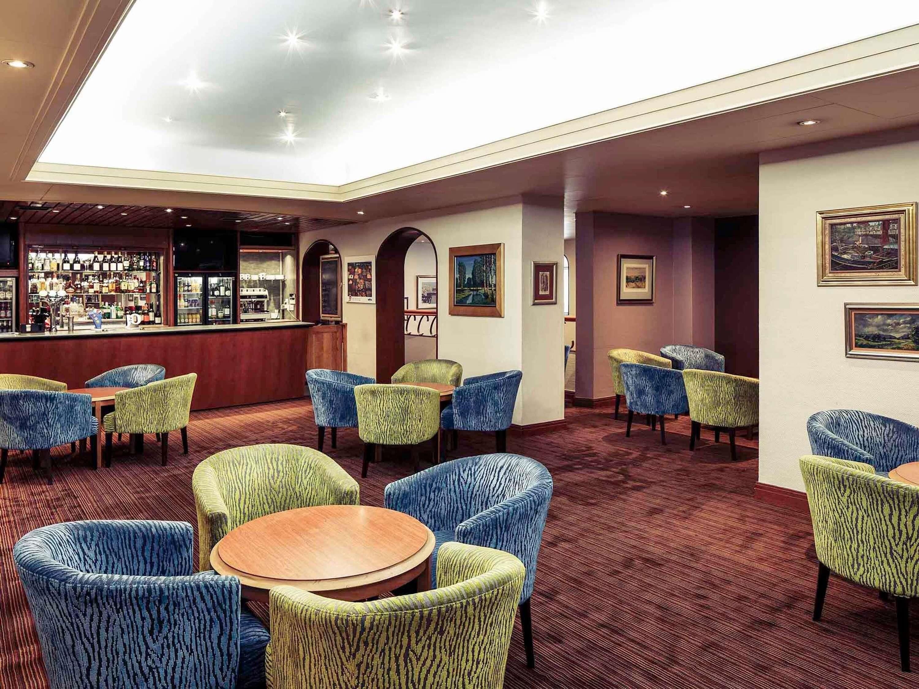 A hotel lobby with a bar area, seating arrangements, and artwork on the walls.