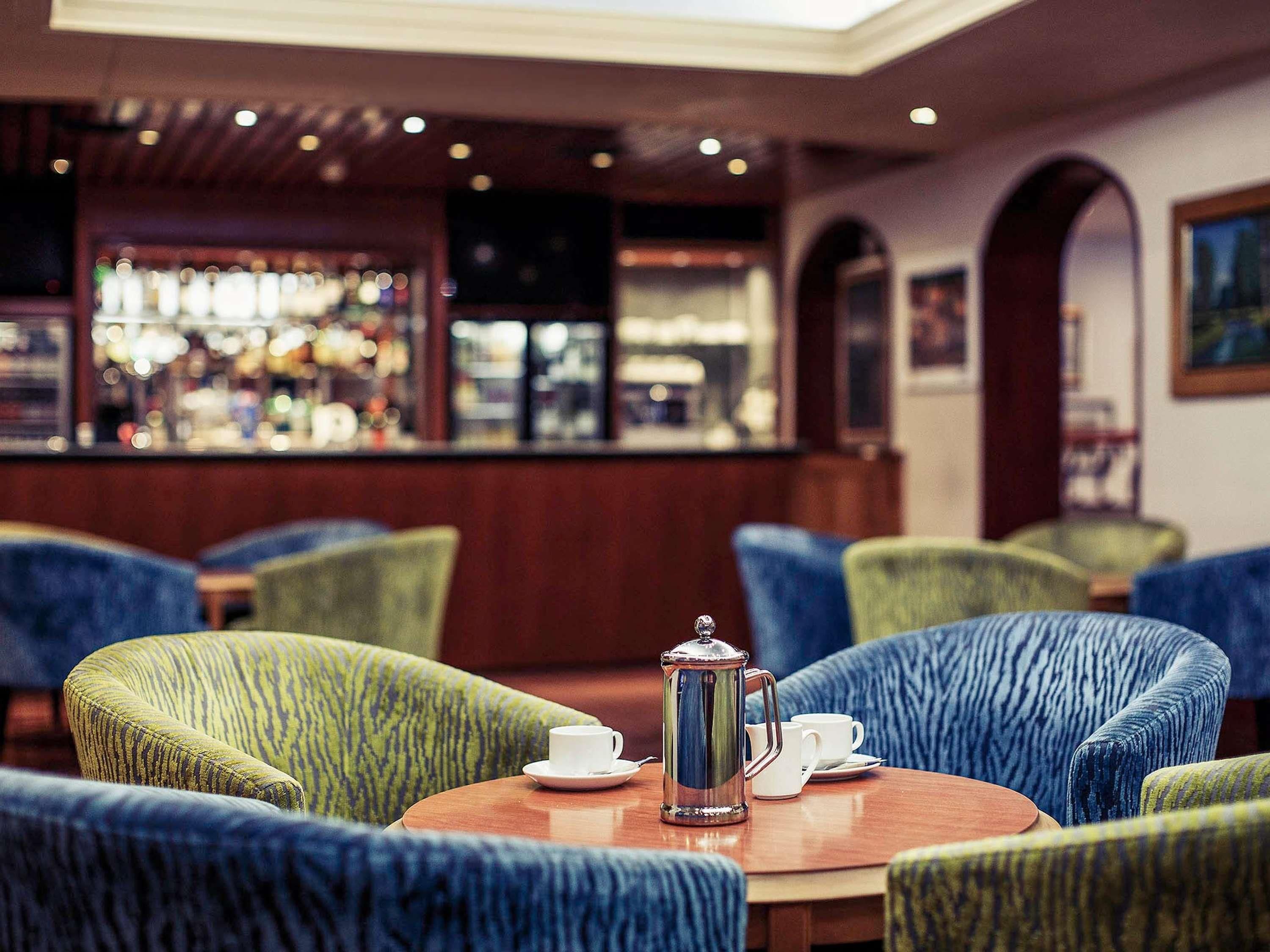A bar area with a coffee table, chairs, and a coffee pot.