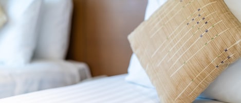 A neatly made bed with white bedding and a single decorative pillow.