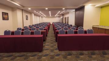 A conference room with rows of tables and chairs, carpeted floor, and a door on the right.