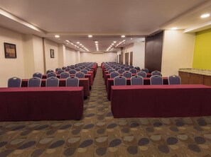 A conference room with rows of tables and chairs, carpeted floor, and a door on the right. - Krystal Urban Monterrey (Monterrey)