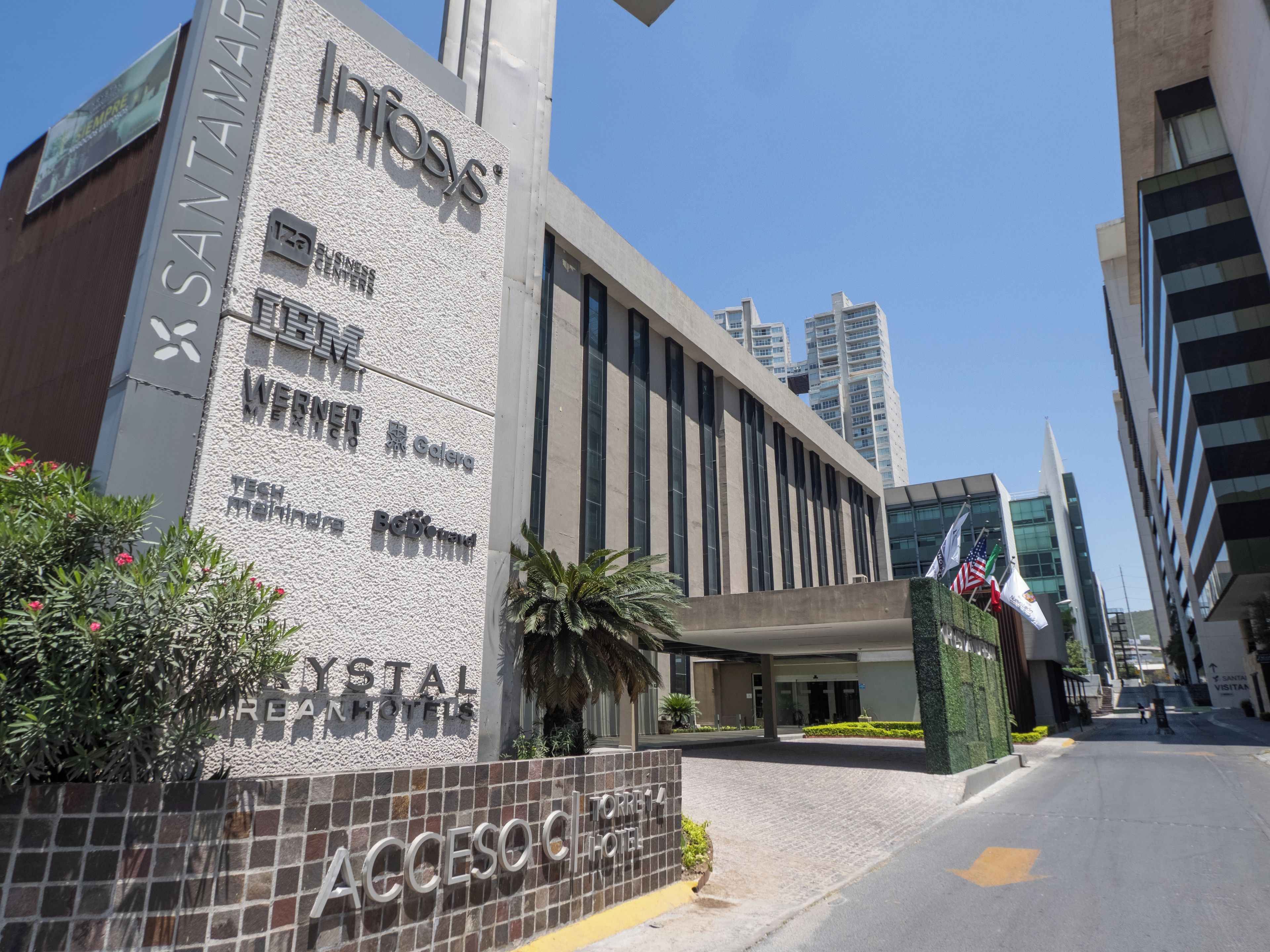A modern building with signage for Infosys, a business center, and a hotel named Crystal Dreams.