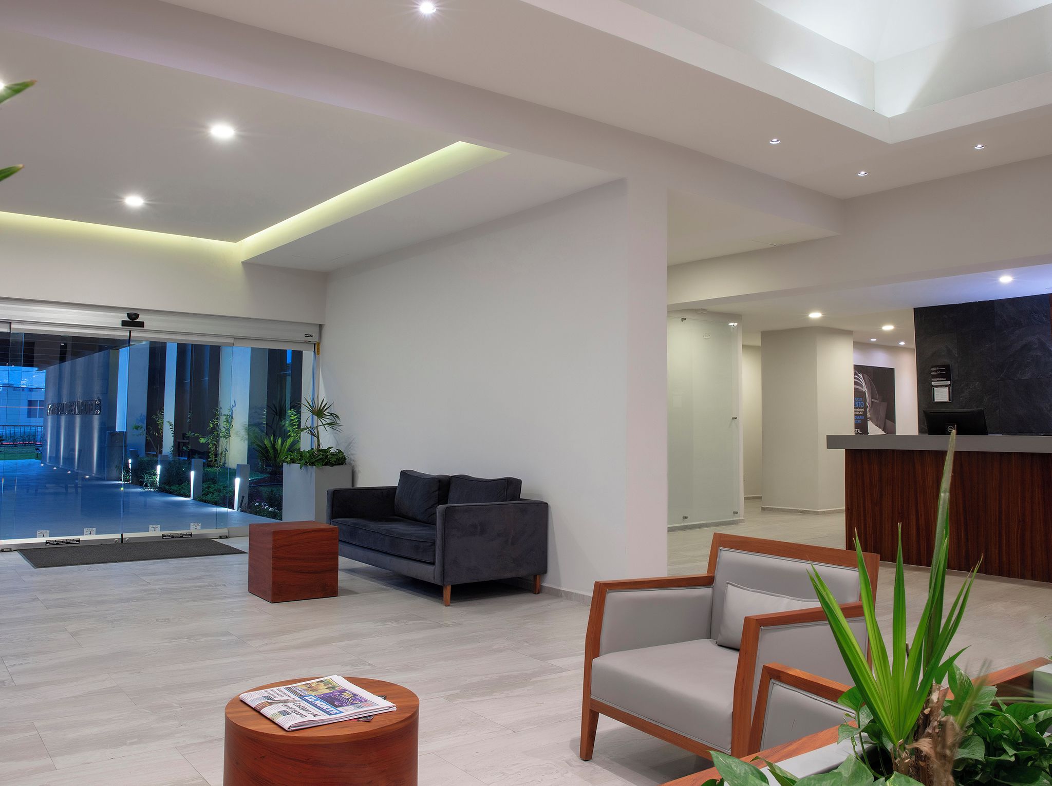 A modern reception area with a sofa, a wooden side table, and a reception desk.