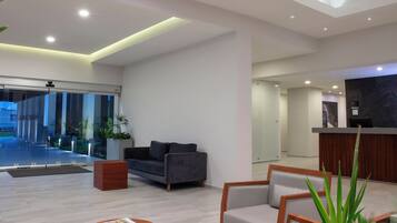 A modern reception area with a sofa, a wooden side table, and a reception desk.