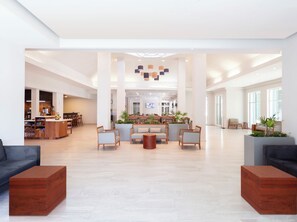A spacious lobby with a reception desk, seating area, and a large TV screen. - Krystal Urban Monterrey (Monterrey)