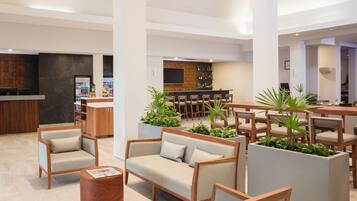 Un vestíbulo moderno con zonas de estar, un bar y una recepción.