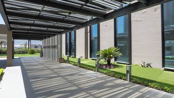 A covered walkway with a modern design, large windows, and a well-maintained lawn.
