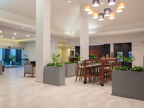 A spacious indoor area with a reception desk, seating area with wooden chairs, and potted plants. - Krystal Urban Monterrey (Monterrey)