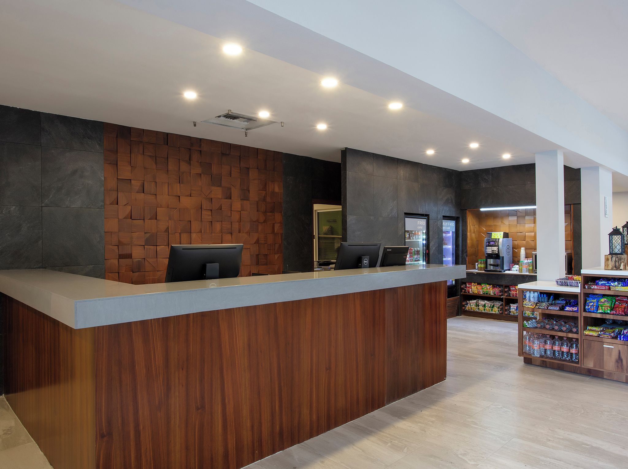 Un comptoir d’accueil avec un panneau décoratif en bois, une machine à café et un présentoir de collations.