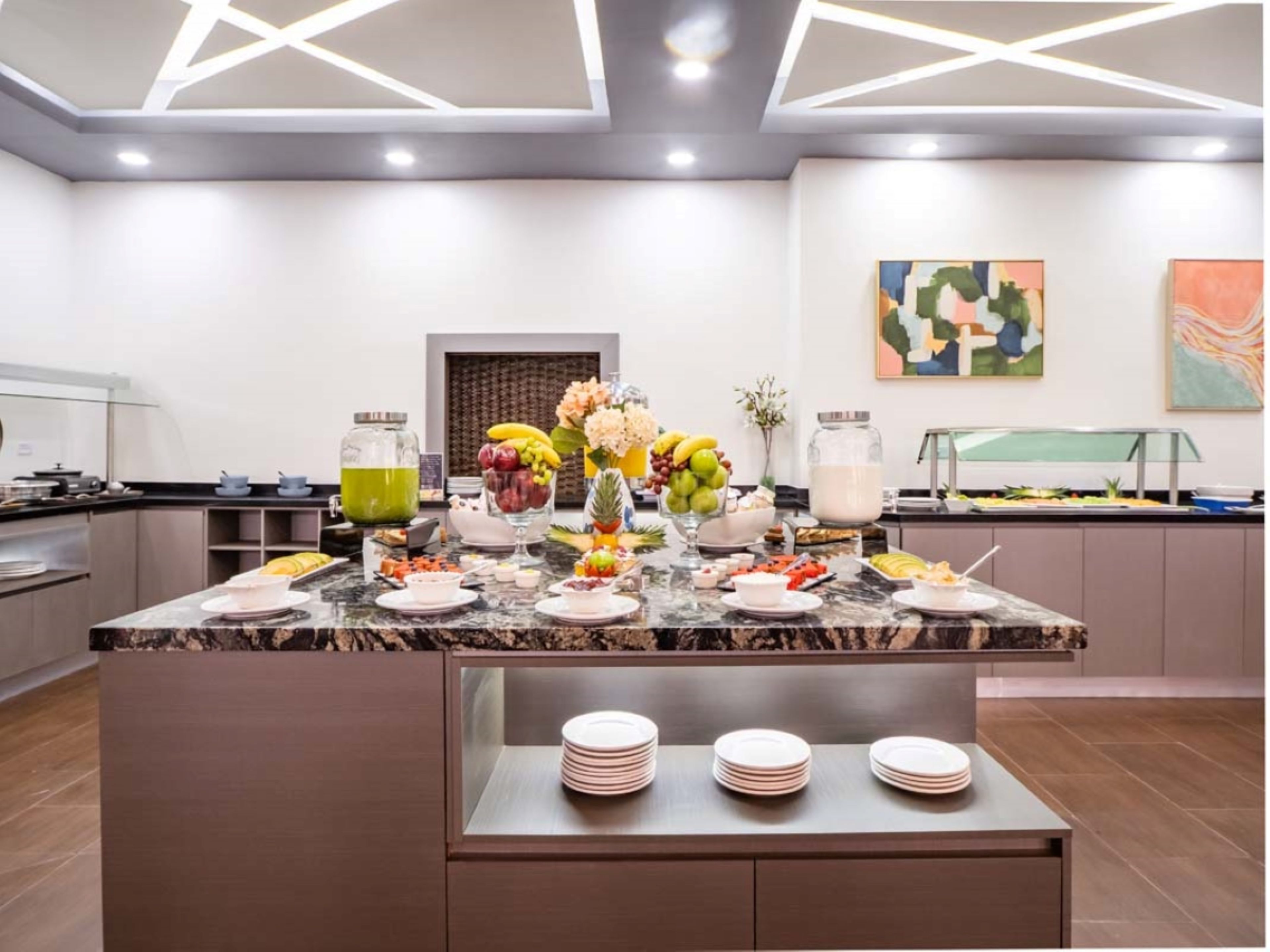 A modern kitchen with a marble countertop, a fruit display, and a buffet area.