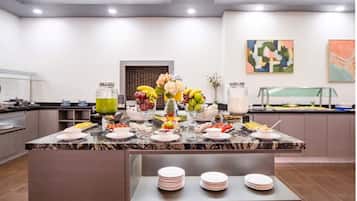 A modern kitchen with a marble countertop, a fruit display, and a buffet area.