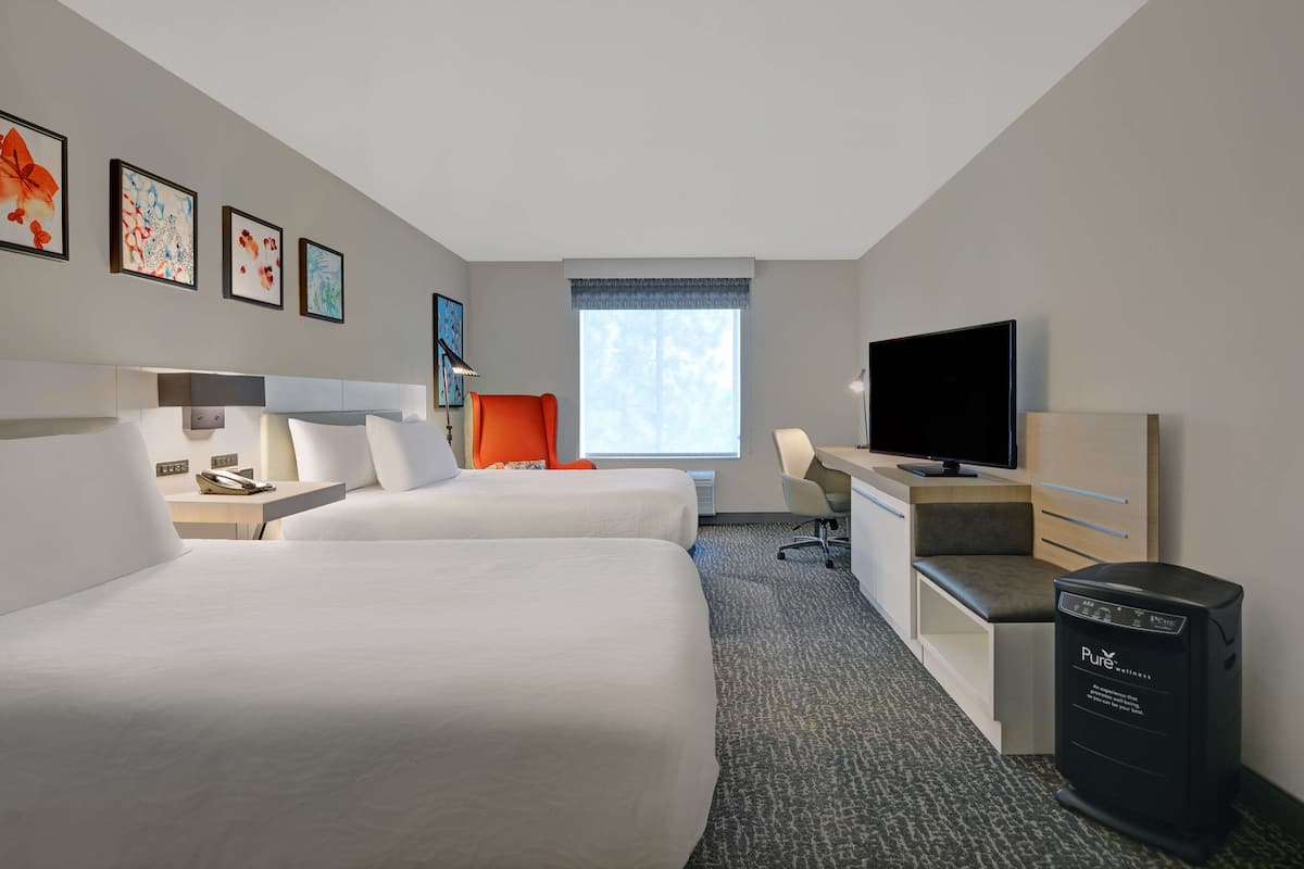 Une chambre d’hôtel avec deux lits, un bureau, une télévision et un minibar.
