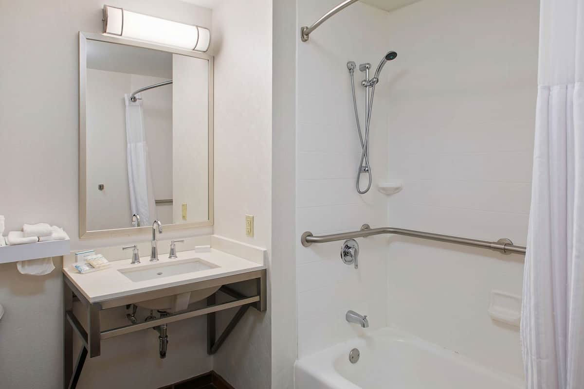 Une salle de bain équipée d’un lavabo, d’un miroir, d’une douche et d’une baignoire.