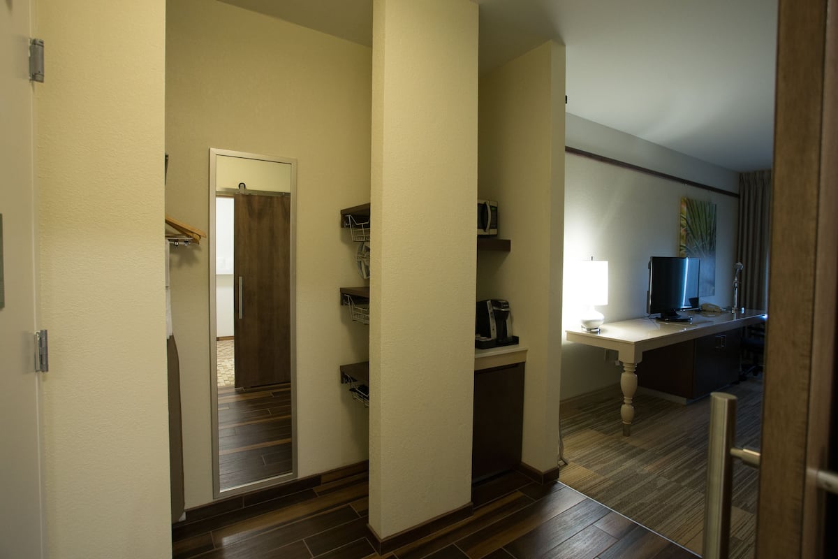 Un couloir avec un plancher en bois, une porte donnant sur une pièce et un comptoir sur lequel se trouvent une lampe et un ordinateur.