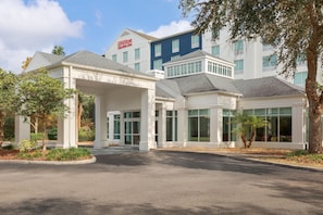 Ein Hilton Garden Inn mit überdachter Eingangspartie, mehreren Fenstern und einem Parkplatz.