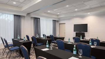 A conference room with tables, chairs, and a television screen.