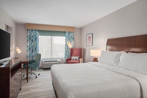 Ein Hotelzimmer mit Bett, Schreibtisch, Stuhl und Fernseher.
