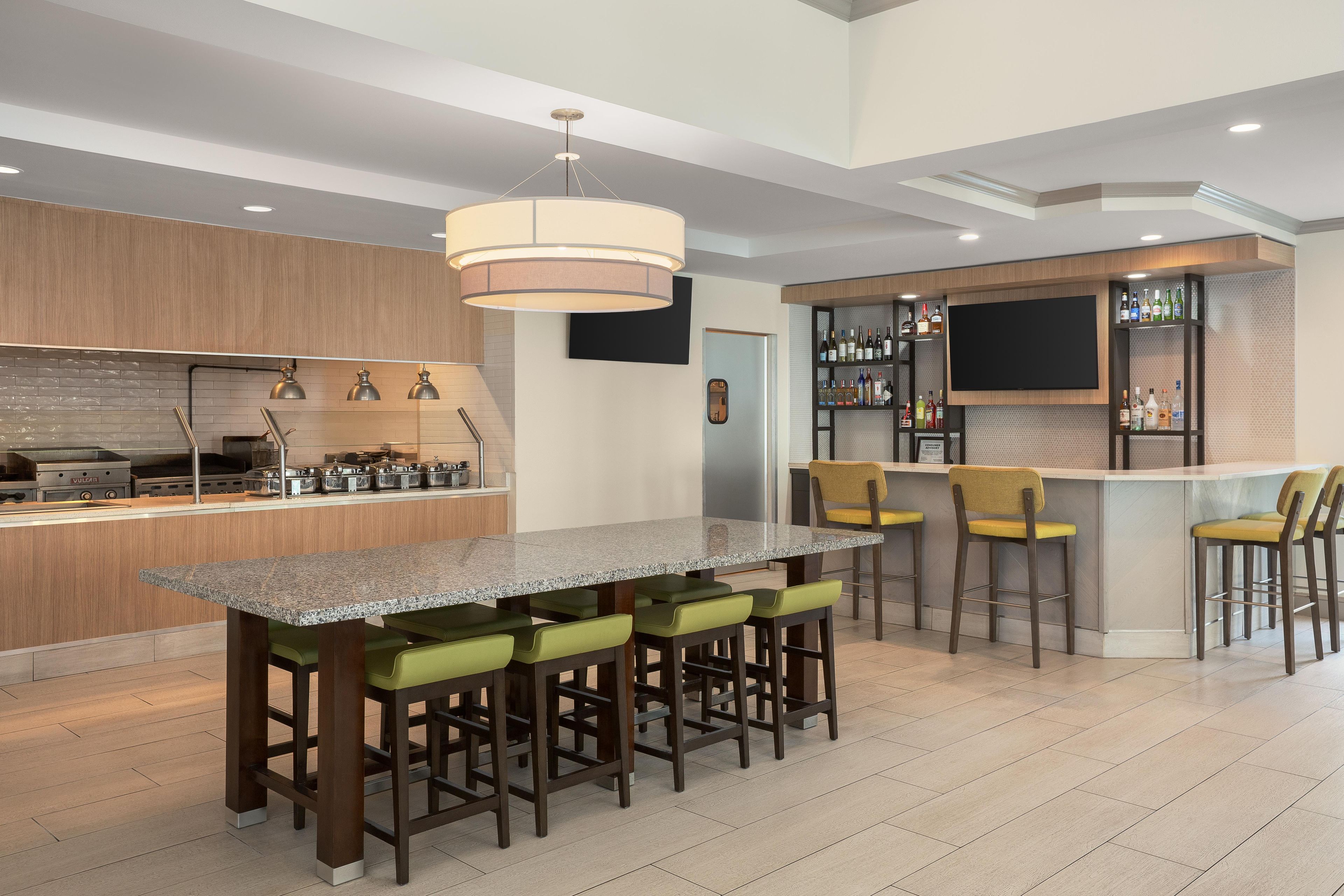Una cocina moderna con barra, que incluye una encimera de granito, taburetes de bar y una estantería para vinos.