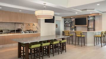 Una cocina moderna con barra, que incluye una encimera de granito, taburetes de bar y una estantería para vinos.