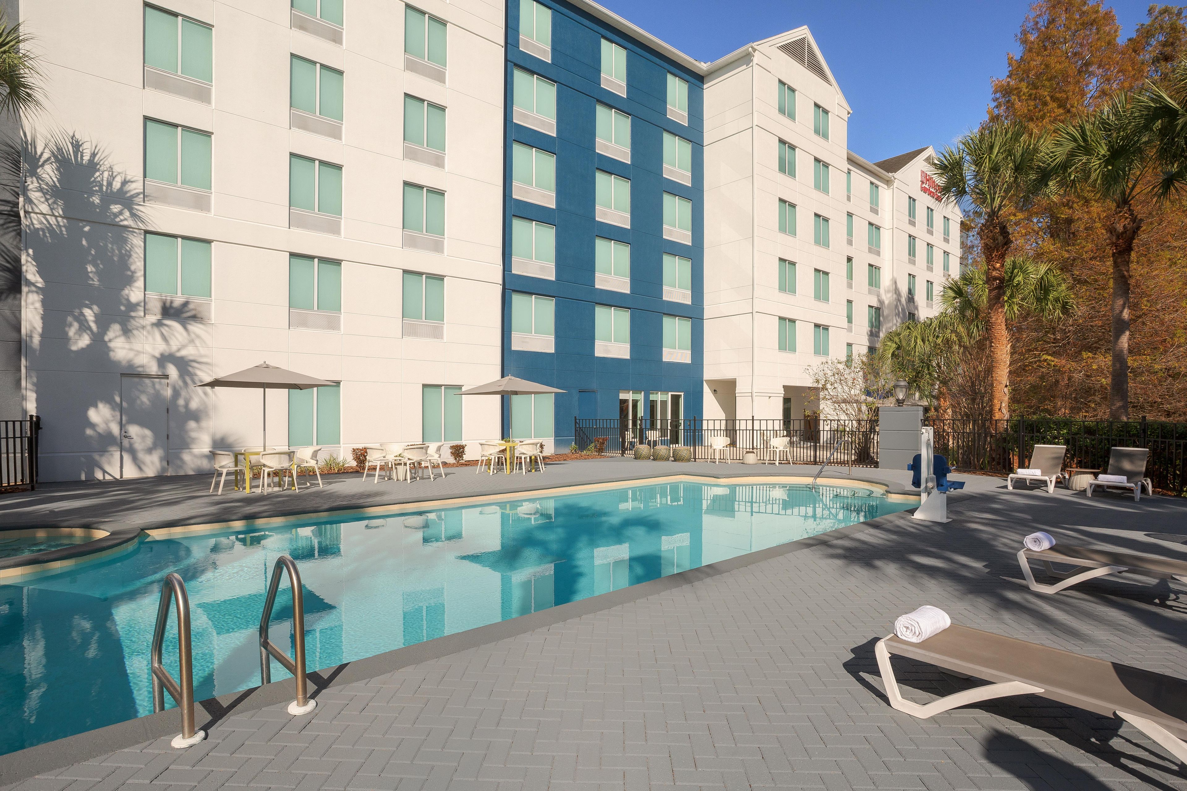Un hôtel doté d’une piscine, d’un espace extérieur aménagé et d’un immeuble à plusieurs étages avec de grandes fenêtres.