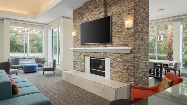 Una sala de estar moderna con chimenea de piedra, un televisor de pantalla plana, asientos cómodos y ventanas amplias con vistas al exterior.