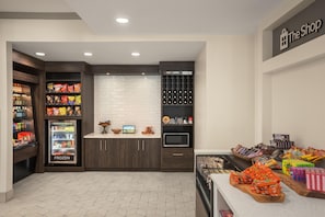 A snack and beverage kiosk with a variety of snacks, a chilled beverage fridge, and a wine cooler section. - Hilton Garden Inn Tampa North Busch Gardens (Tampa)