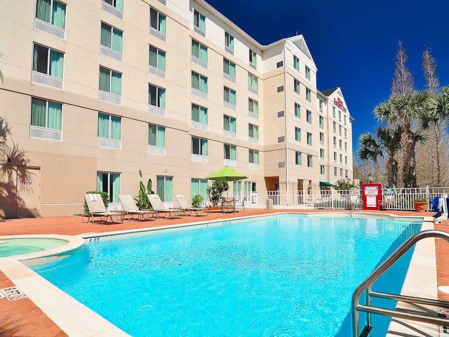 Um hotel com piscina, espreguiçadeiras e palmeiras.