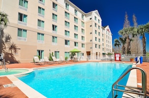 Un hotel con piscina, tumbonas y palmeras.