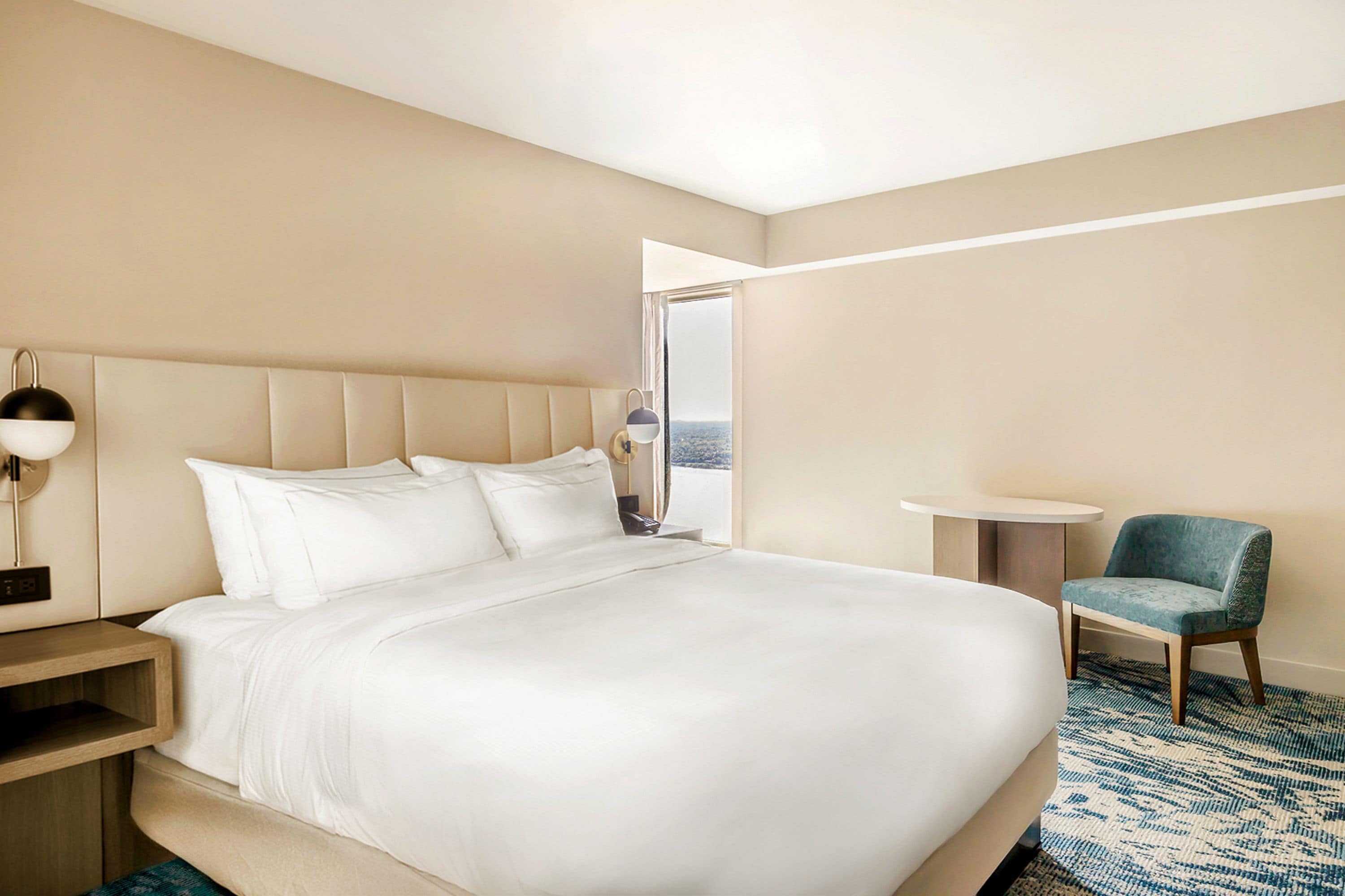 Une chambre d’hôtel avec un grand lit, une table de chevet, une chaise et une petite table.