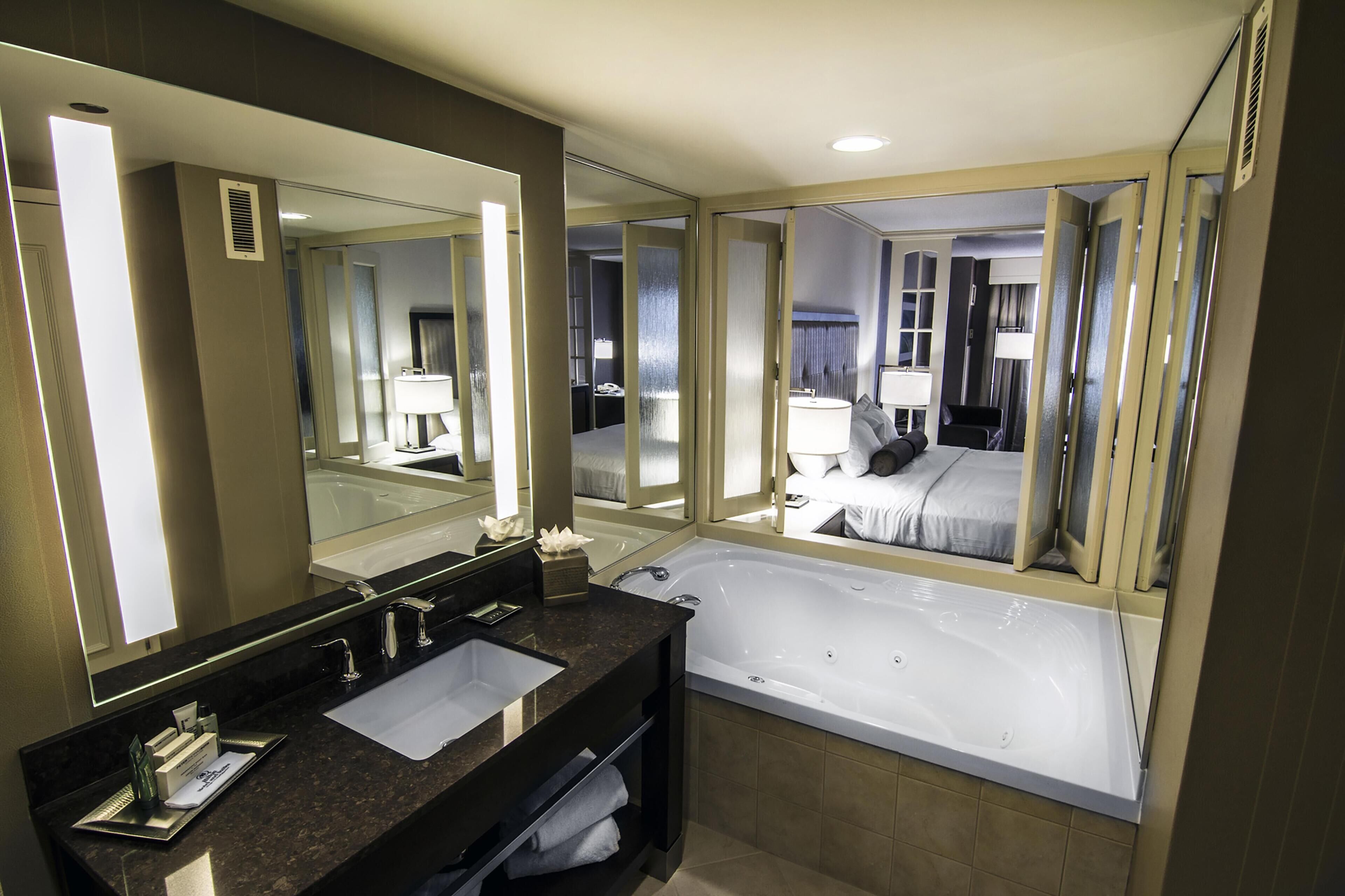 Ein modernes Badezimmer mit einem großen Spiegel, zwei Waschbecken, einer Badewanne und einer Toilette.