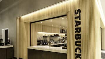Una tienda Starbucks moderna con un diseño minimalista, que presenta un letrero grande iluminado y un interior limpio y contemporáneo.