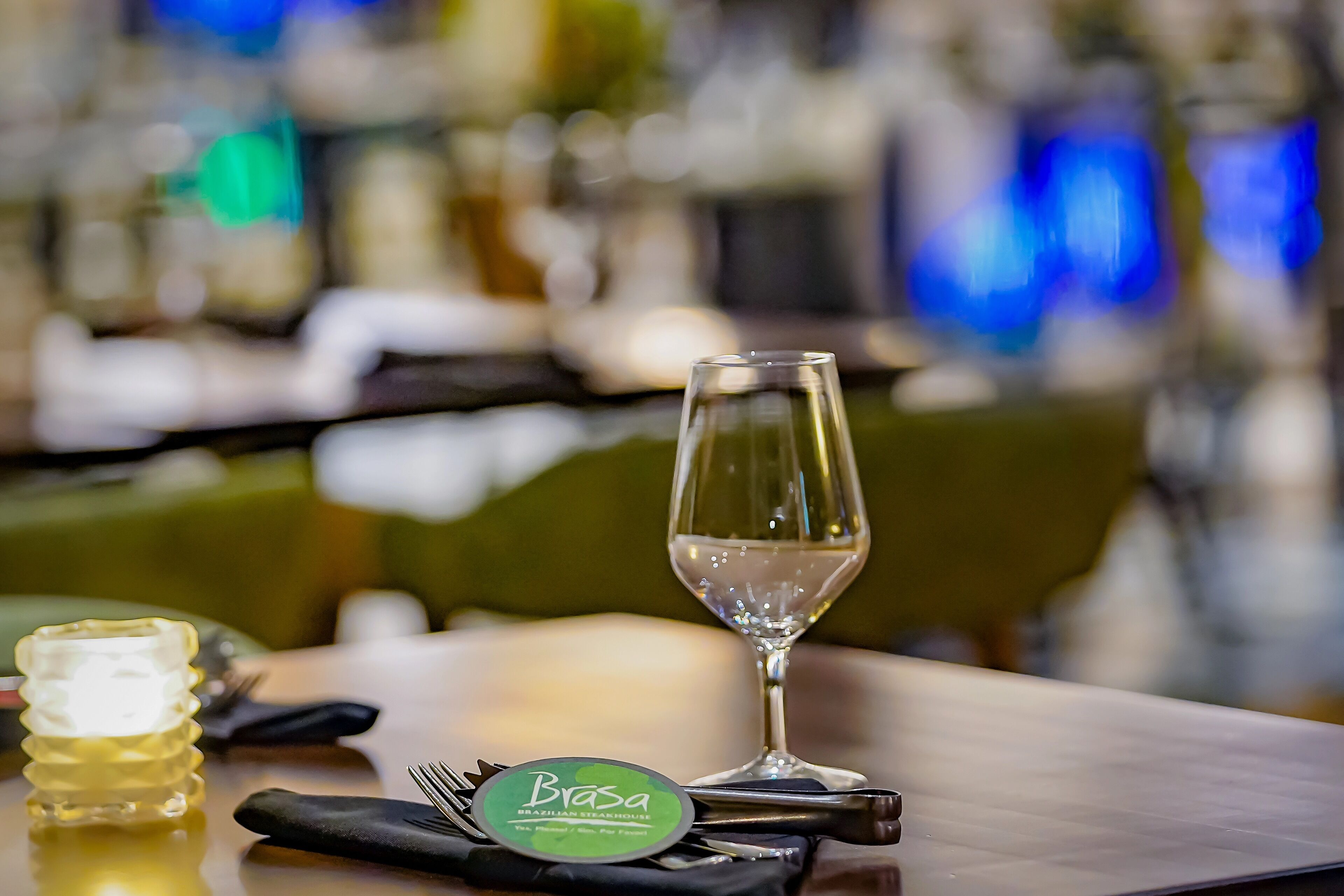 A dining table with a wine glass, a bottle of water, and a napkin with a name tag.