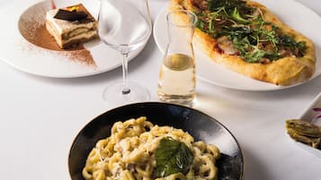 A dining table with various dishes including pasta, pizza, and a dessert.