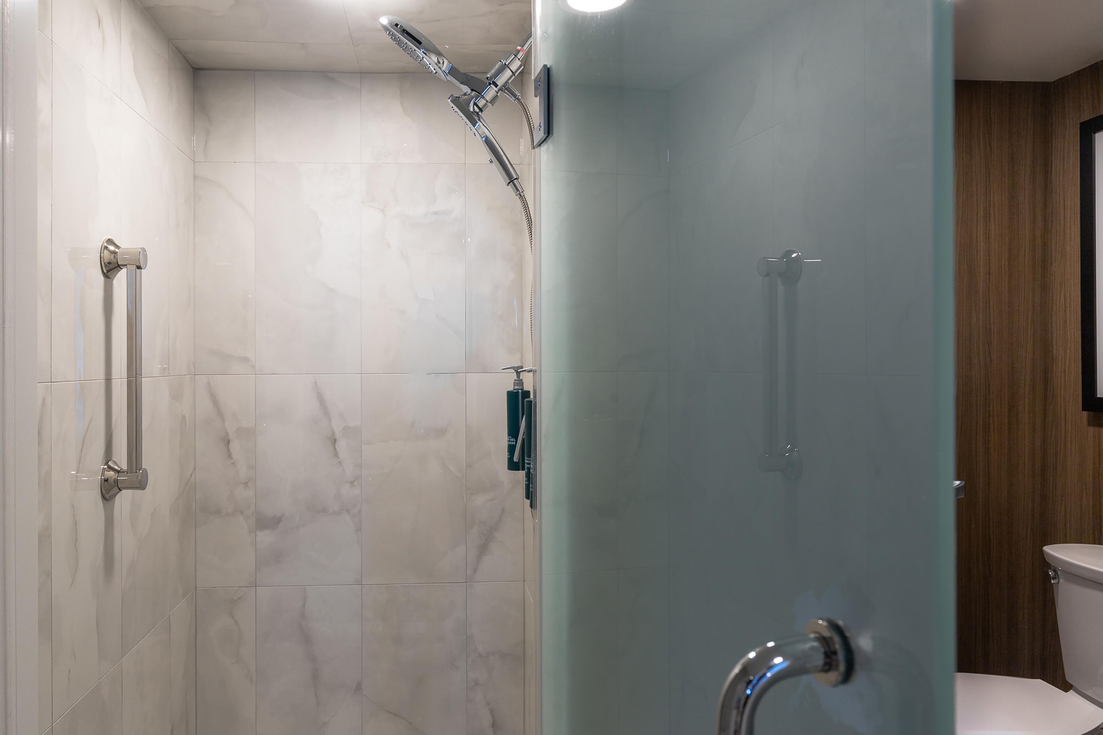 A modern bathroom with a glass shower enclosure, a toilet, and a sink.