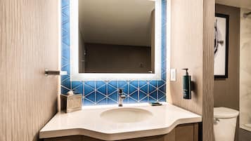 A bathroom with a white sink, a mirror, and blue-tiled walls.