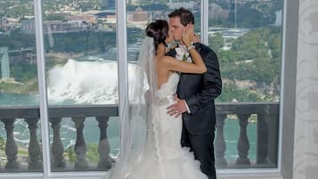 A couple embracing in a room with large windows overlooking a cityscape.