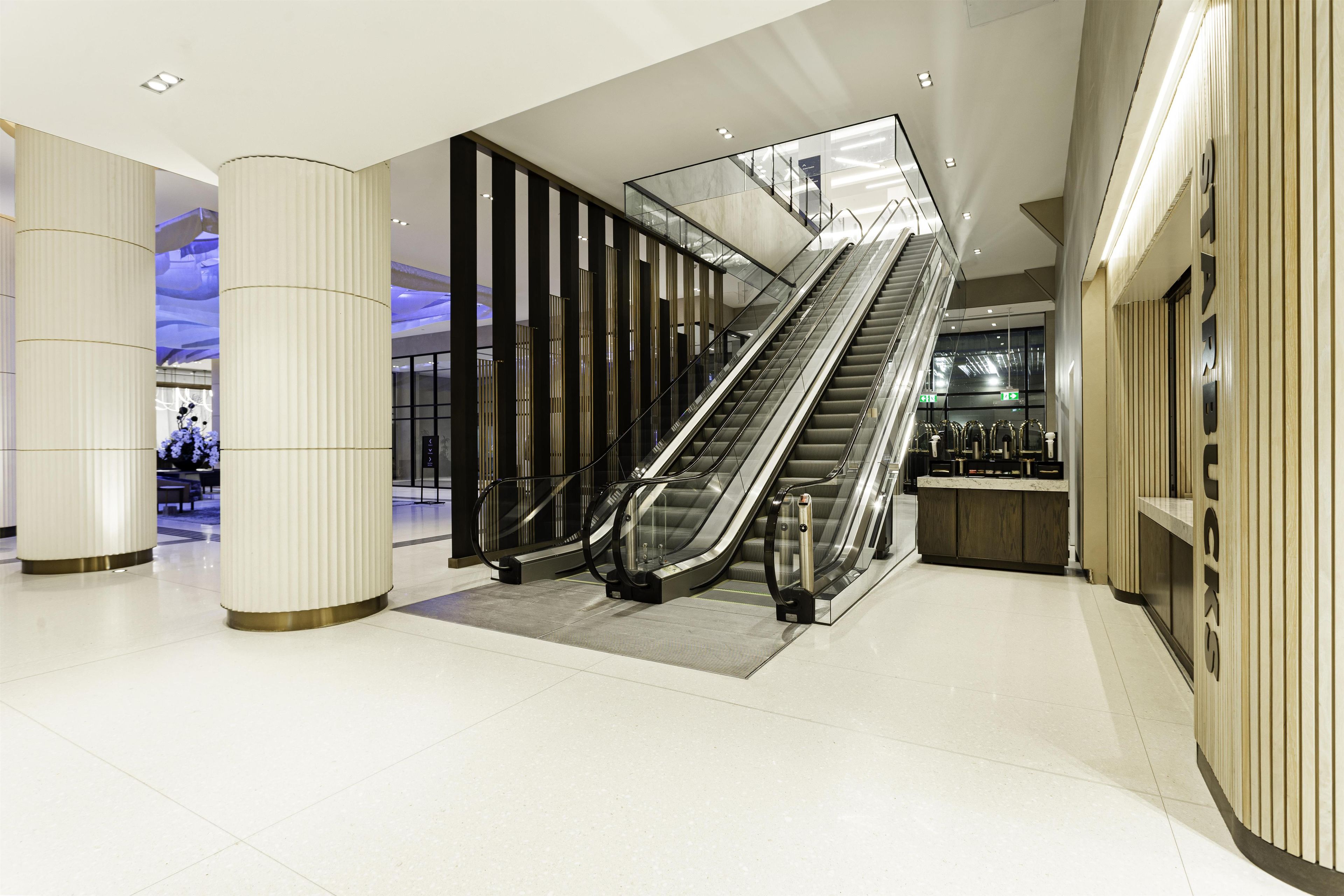 A modern interior with an escalator, a reception desk, and a column.