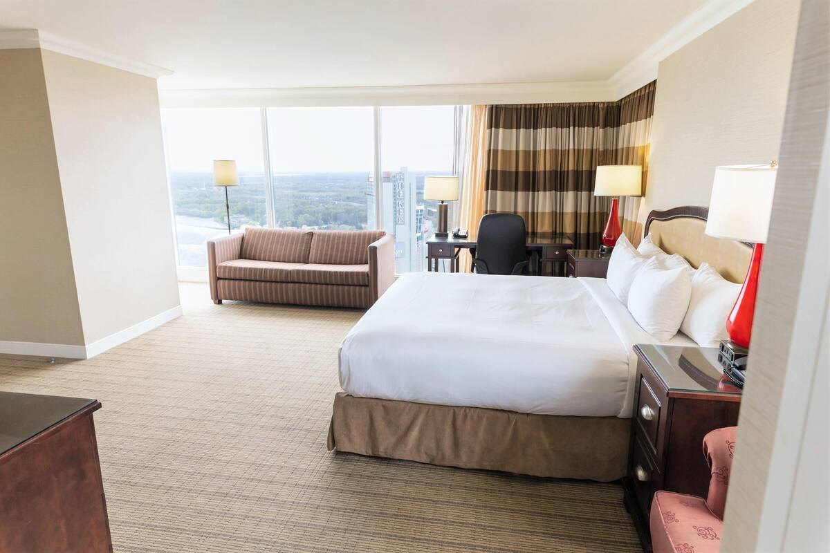 Une chambre d’hôtel avec un grand lit, un canapé, un bureau et une vue sur la ville.