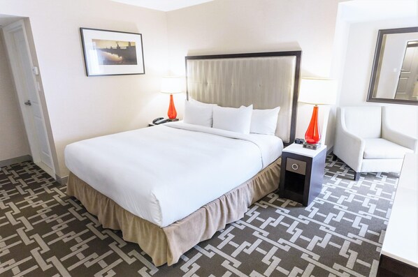 A hotel room with a large bed, bedside tables, a chair, a nightstand with a lamp, and a framed picture on the wall. - Hilton Niagara Falls/Fallsview Hotel & Suites (Niagara Falls)