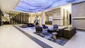 Eine moderne Lobby mit Rezeption, Sitzgelegenheiten und einer großen Zimmerpflanze.