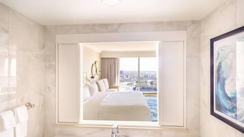 Quarto de hotel com um espelho grande refletindo uma cama e a vista da cidade.