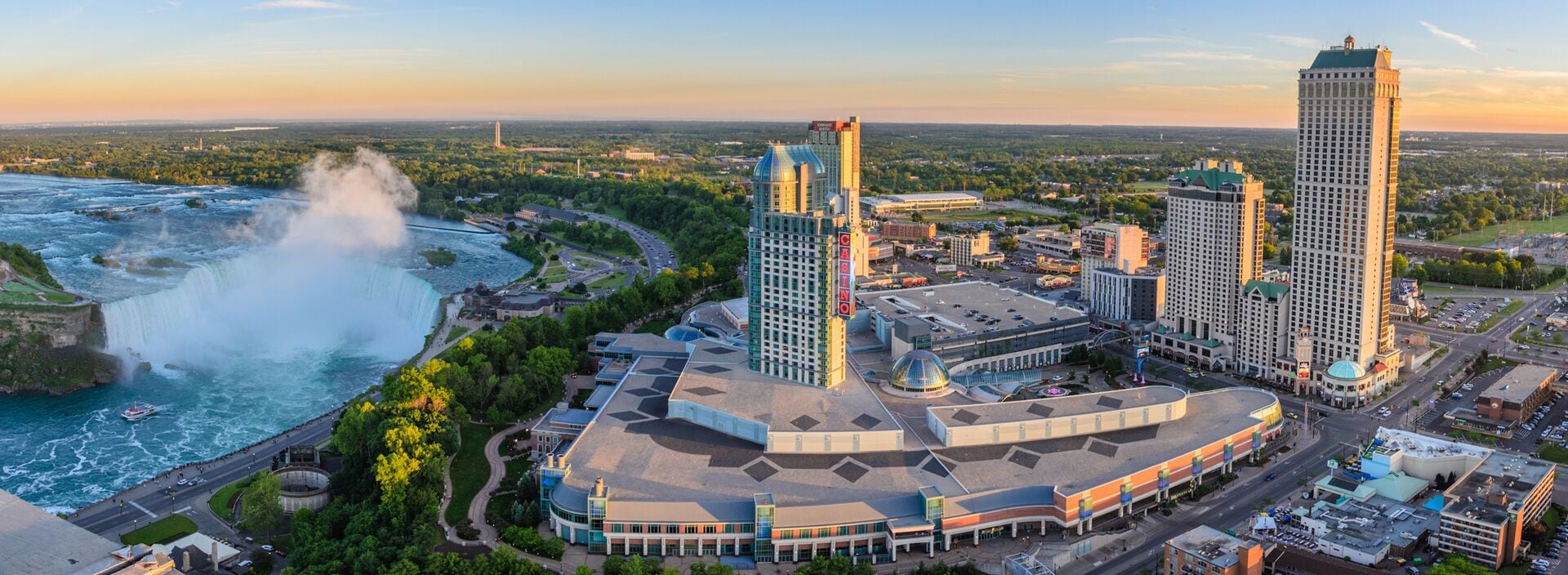 A hotel complex with a central building, two tall towers, and a river with a waterfall.
