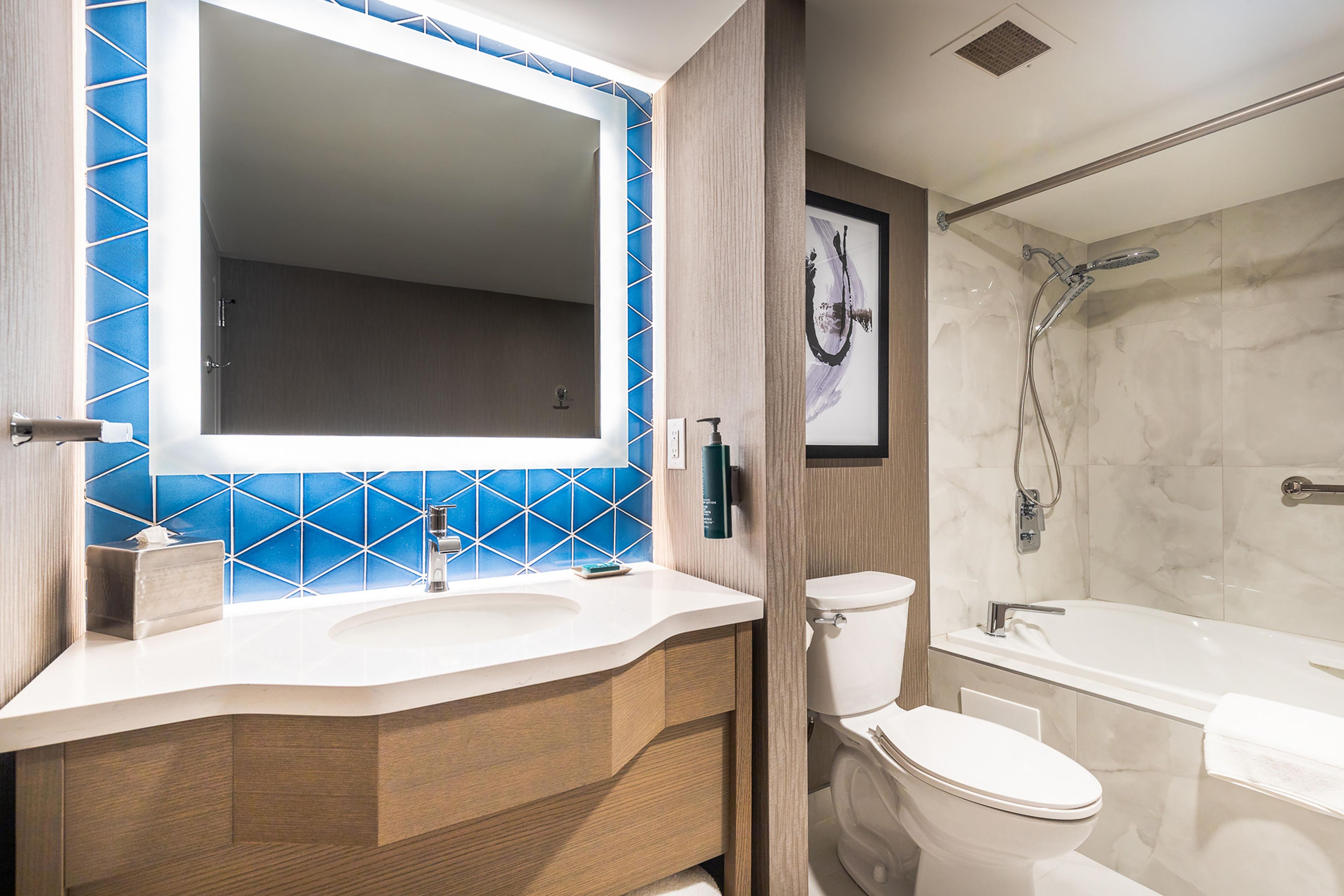 A modern bathroom with a large mirror, a sink, a toilet, and a shower area.