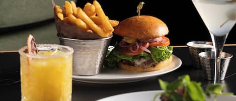 A meal consisting of a burger, fries, a martini, and a drink on a table.