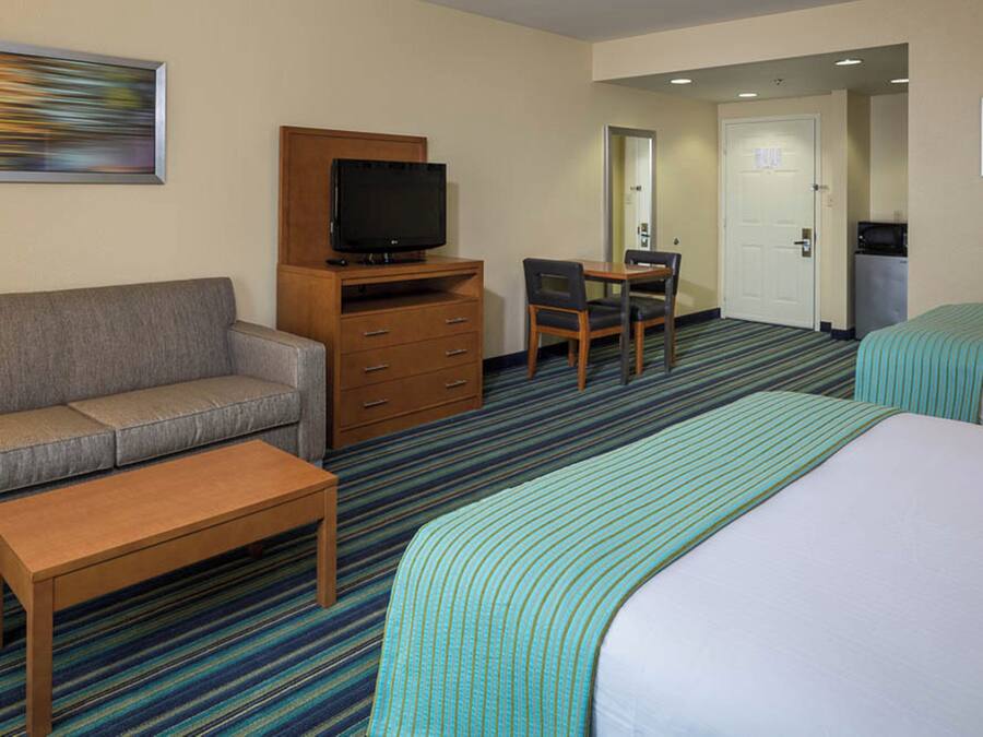 A hotel room with a bed, a sofa, a TV, a desk, and a chair.