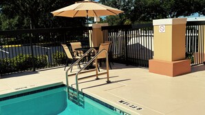 Un espace piscine équipé d’un plongeoir, de chaises longues et d’un parasol.